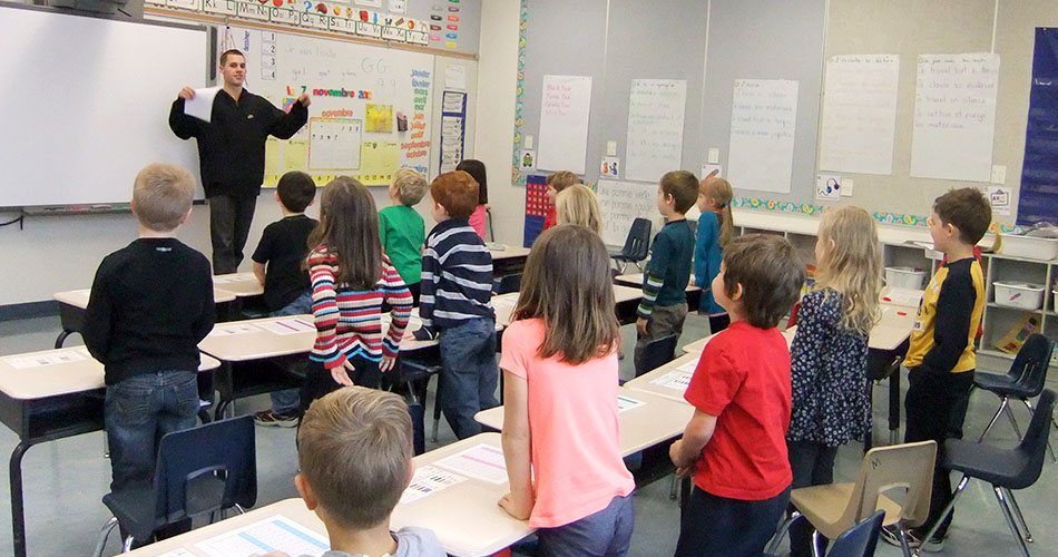 A photo of a teacher in front of a class of elementary students.