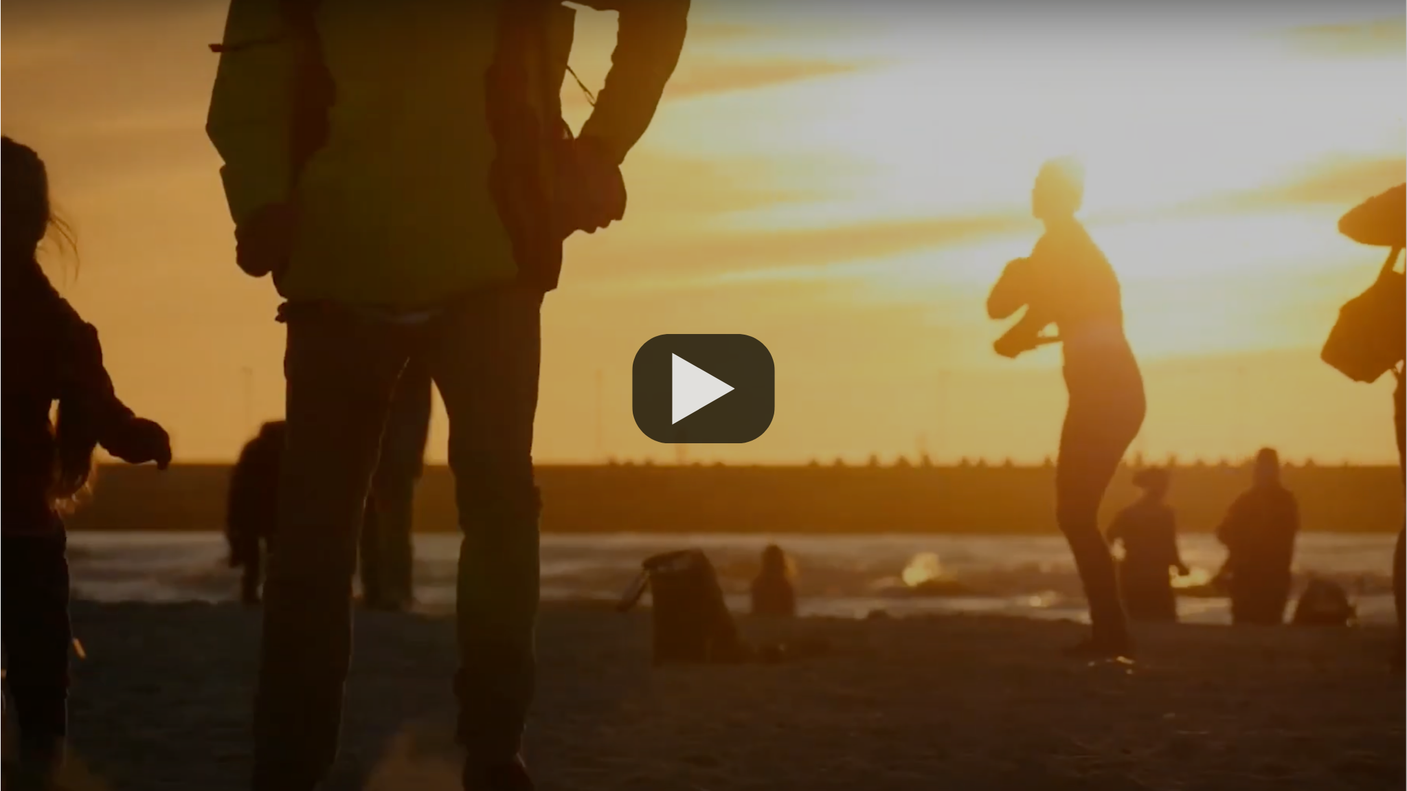 Scenic photo at sunset of a family outside playing. Thumbnail from a video with a clickable play button.