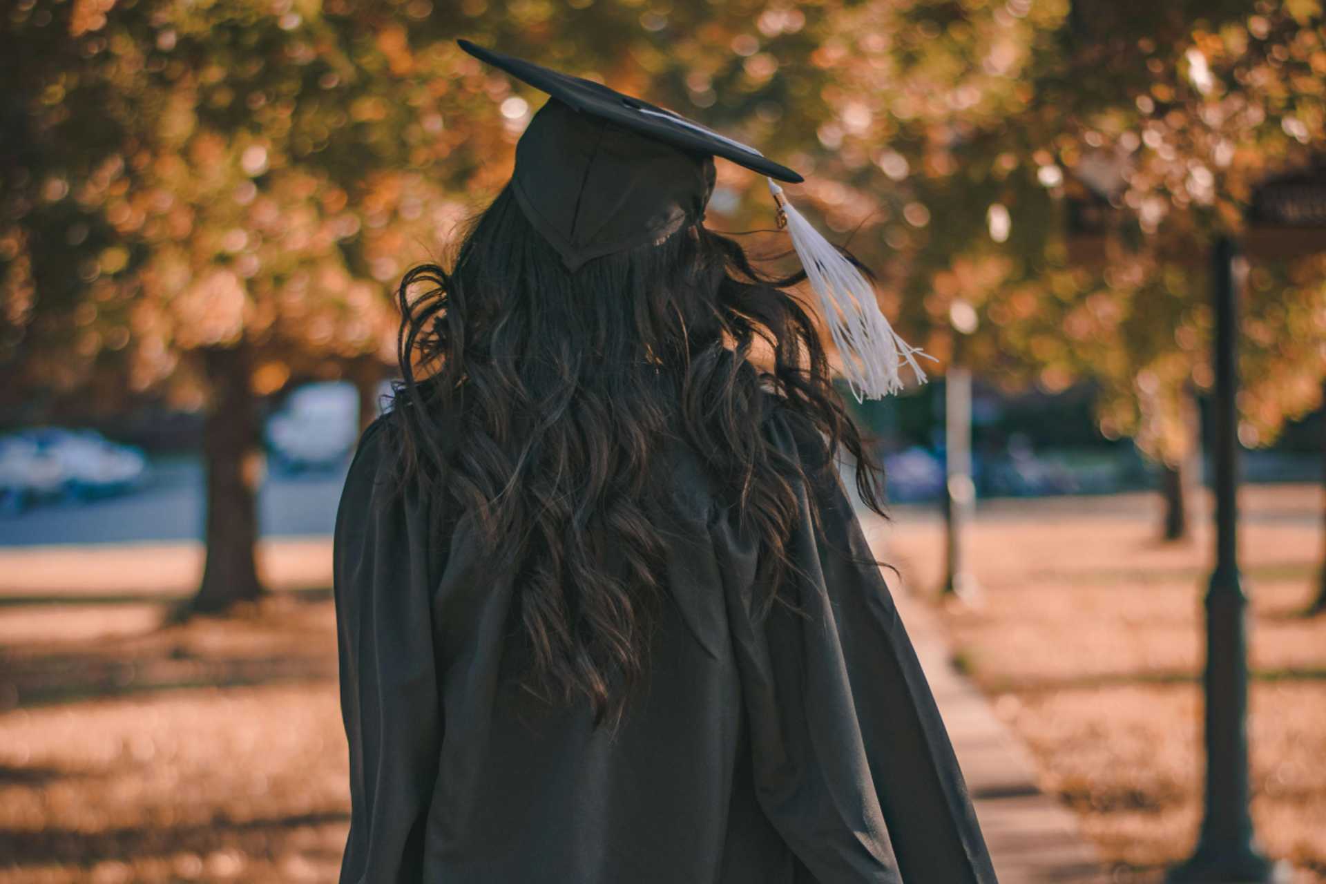 Woman walking away with grad hat and robe on