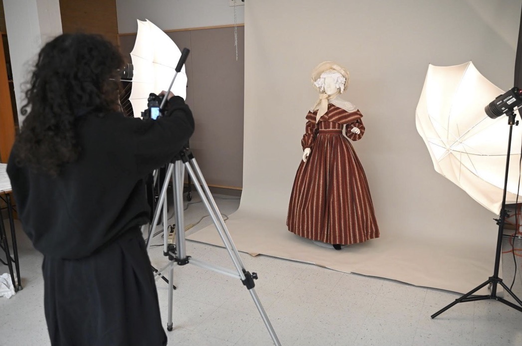  photographer stages a photo of an antiquated dress on a mannequin 