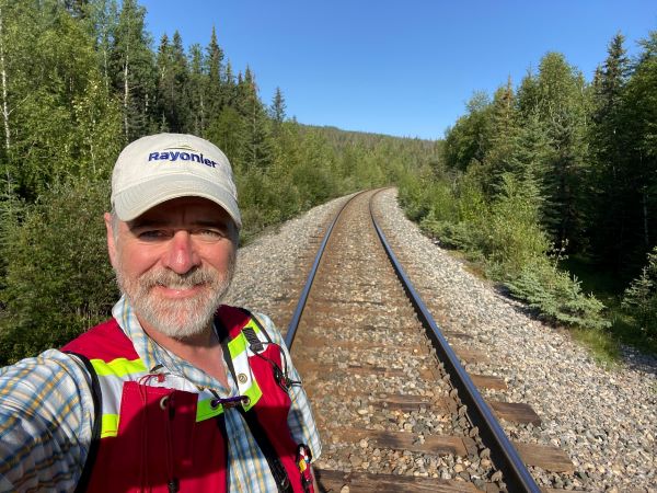 A photo of Robert standing on a railroad track in a forested area.