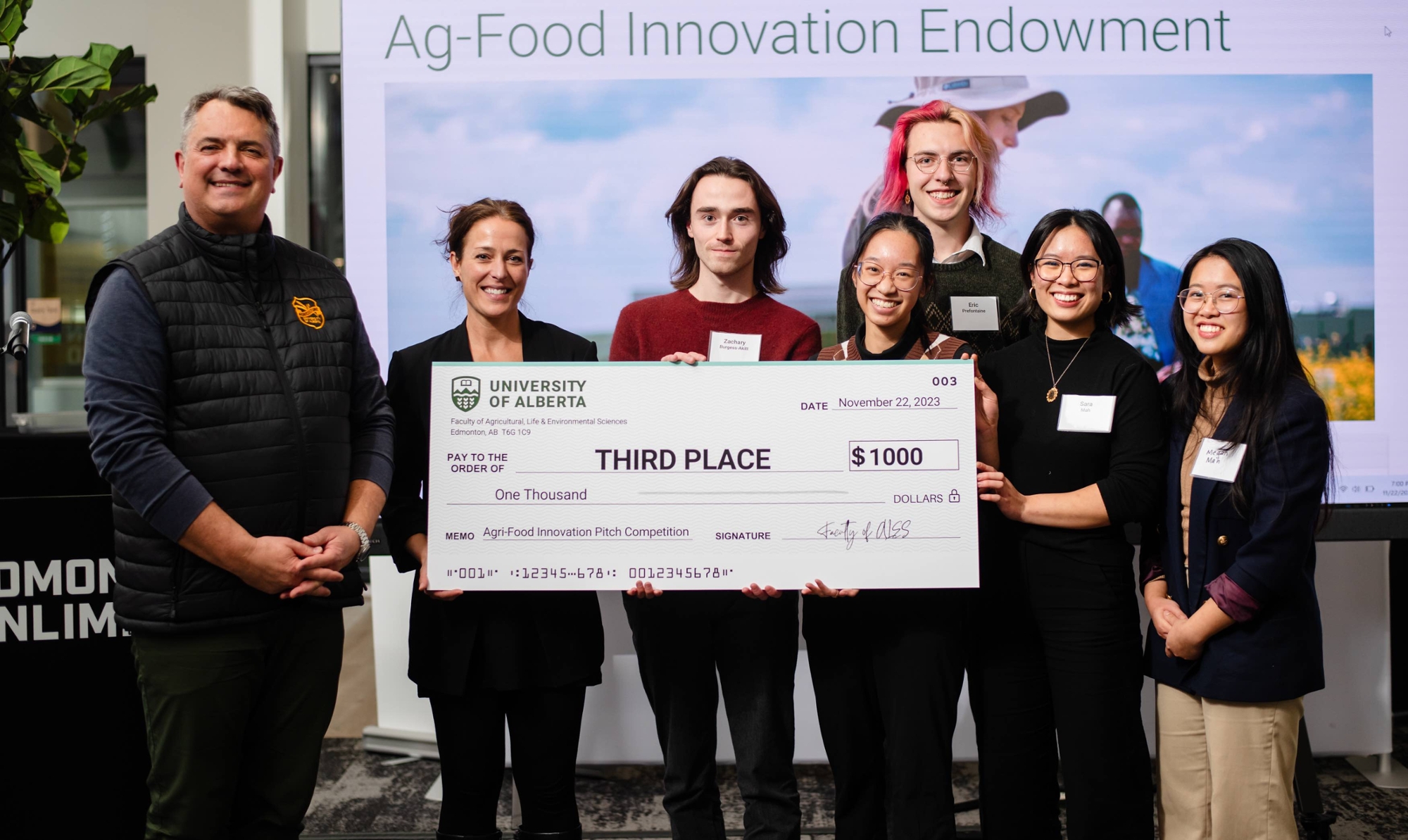 team of students pose with an oversized cheque for $1,000