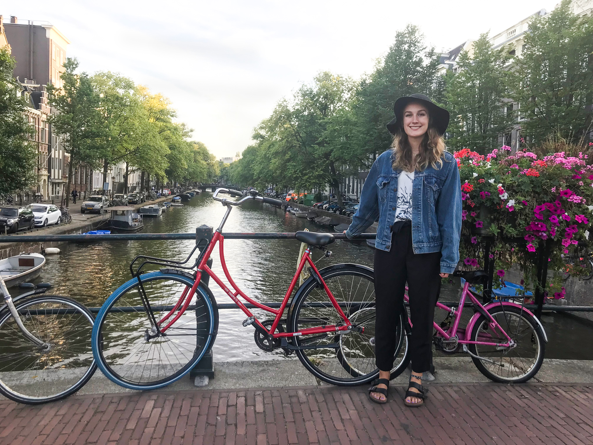 Lauren poses with a bike on a bridge over a canal in a setting that looks European