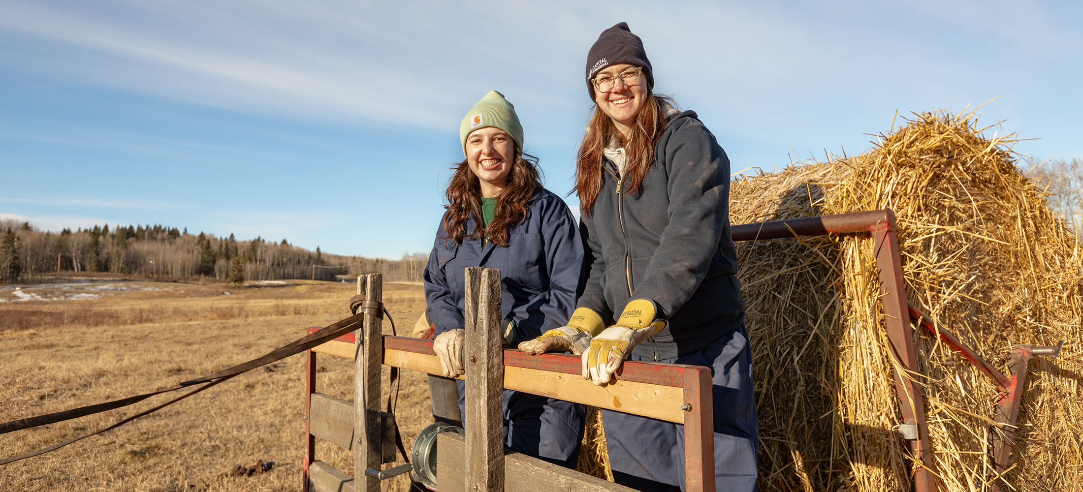 two young university students smile atop a wagon on a farm