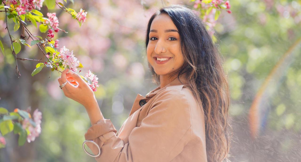 fashion student Ilahinoor poses outside surrounded by flowers