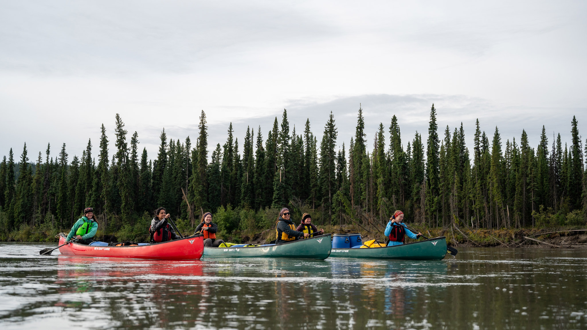 students canoeing with in a scenic cloudy forest landscape