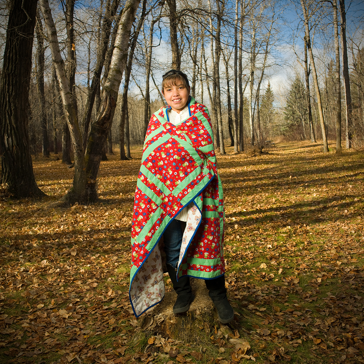 Keisha standing in amongst a field with trees, wrapped in a blanket in 2007