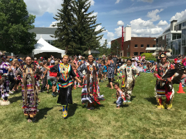 A group of Indigenous community members demonstrating a traditional dance to Augustana students