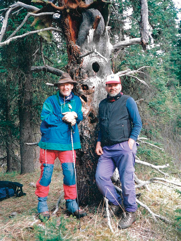 Photo of Garry Gibson and Doc Larsen leaning against a tree in outdoors clothing.