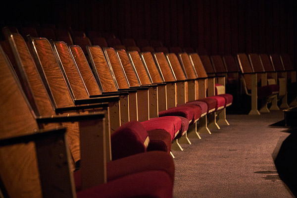 A photo of empty red auditorium chairs in a row. 