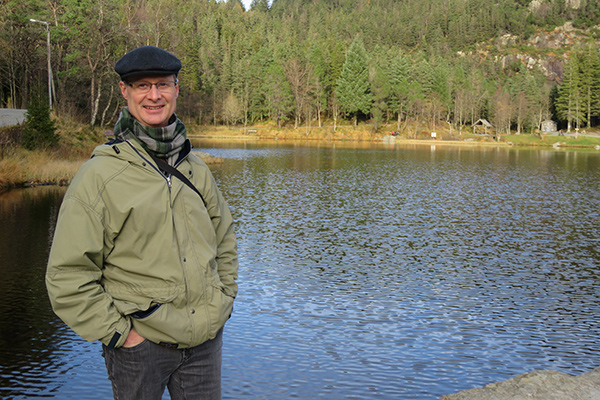 Professor Haave stands in front of a lake smiling at the camera.
