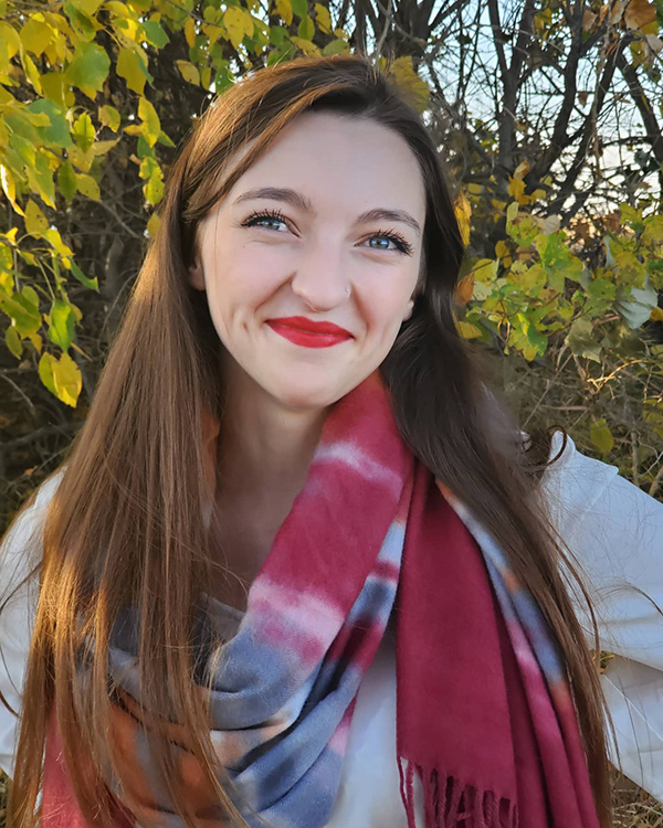 A photo of Rebecca Nicholson, VP communications with the ASA, in a scarf with leaves behind her.