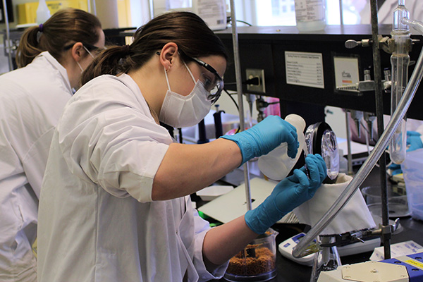 Two students wearing lab gear working on an experiment.