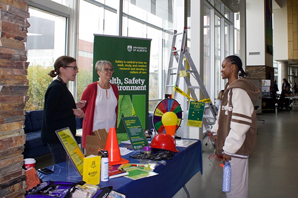A student speaking to two staff members at a safety booth at Augustana Safety Day 2023.
