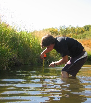 A student with a measuring tape in the water