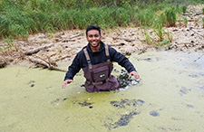 A photo of a student wading through pond water