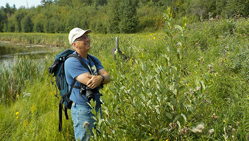 Glen Hvenegaard on a research trip in a grassy field.