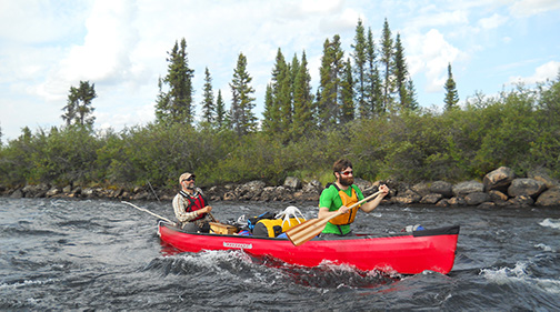 A photo of Greg King and another man canoeing down a river