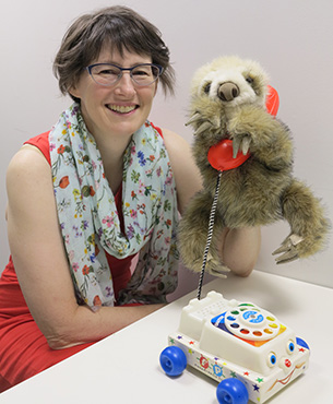 A photo of Paula Marentette with a puppet and child's toy phone