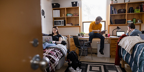 Three students sitting in a first-year dorm room.