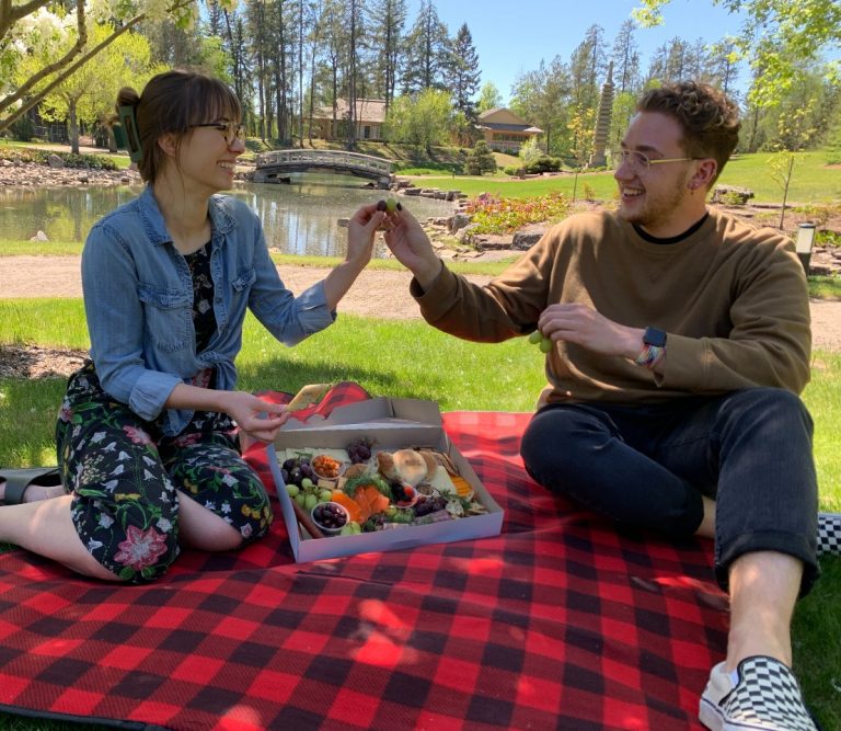 Two people enjoying a chef-created meal before the bridge in the Kurimoto Japanese Garden