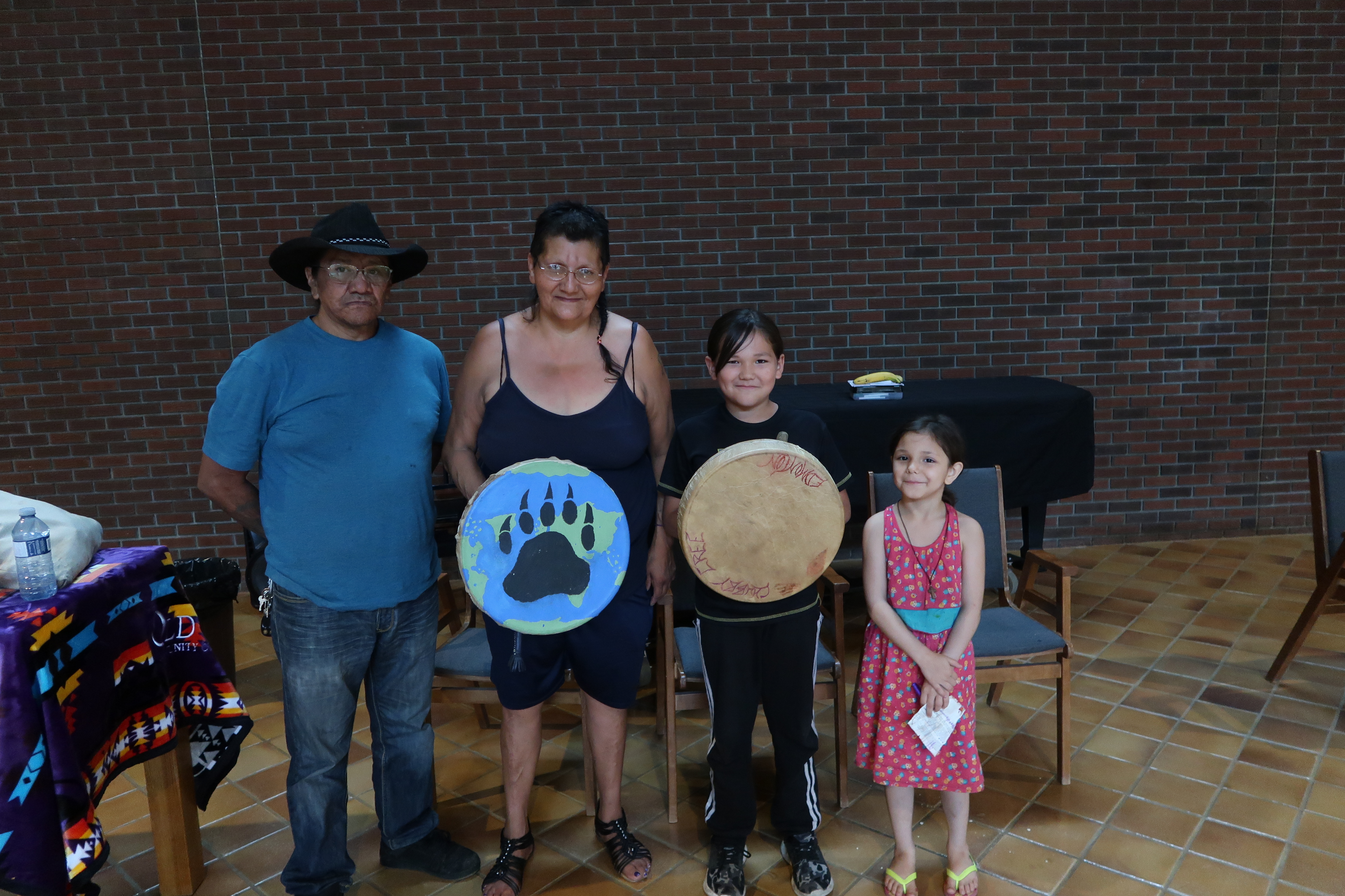 Four people lined up two holding a drum