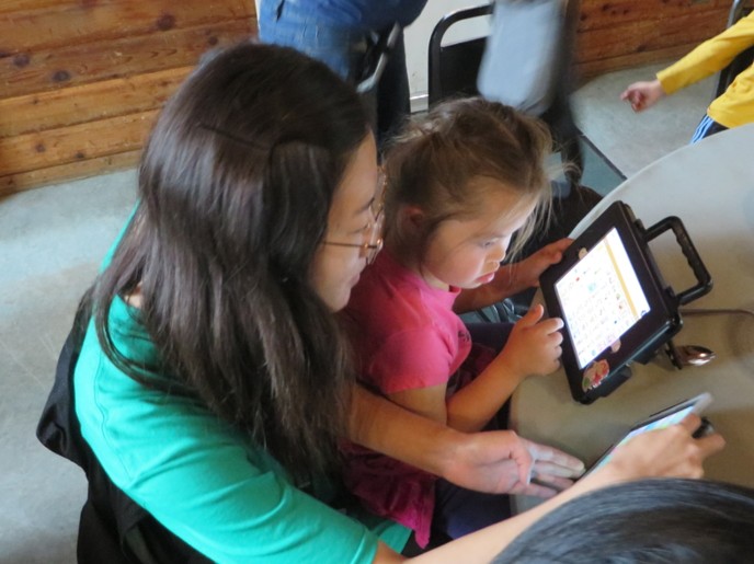 Woman and child using pecs on tablet