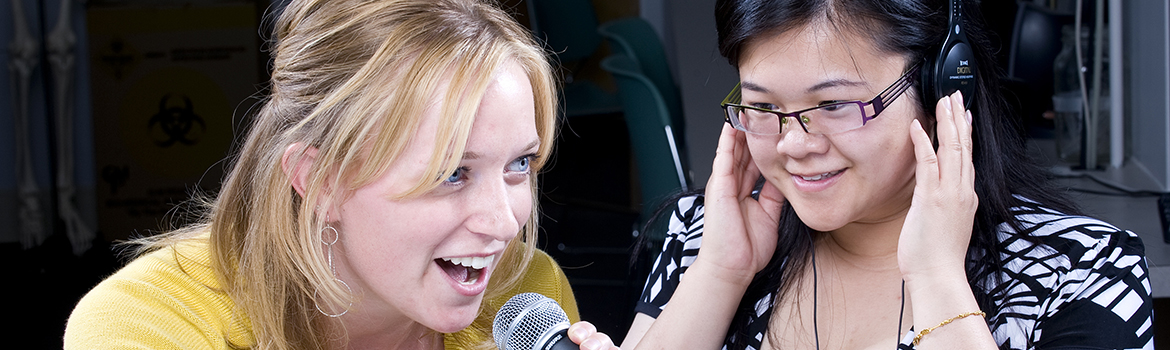 two women one using a microphone and the other using headphones