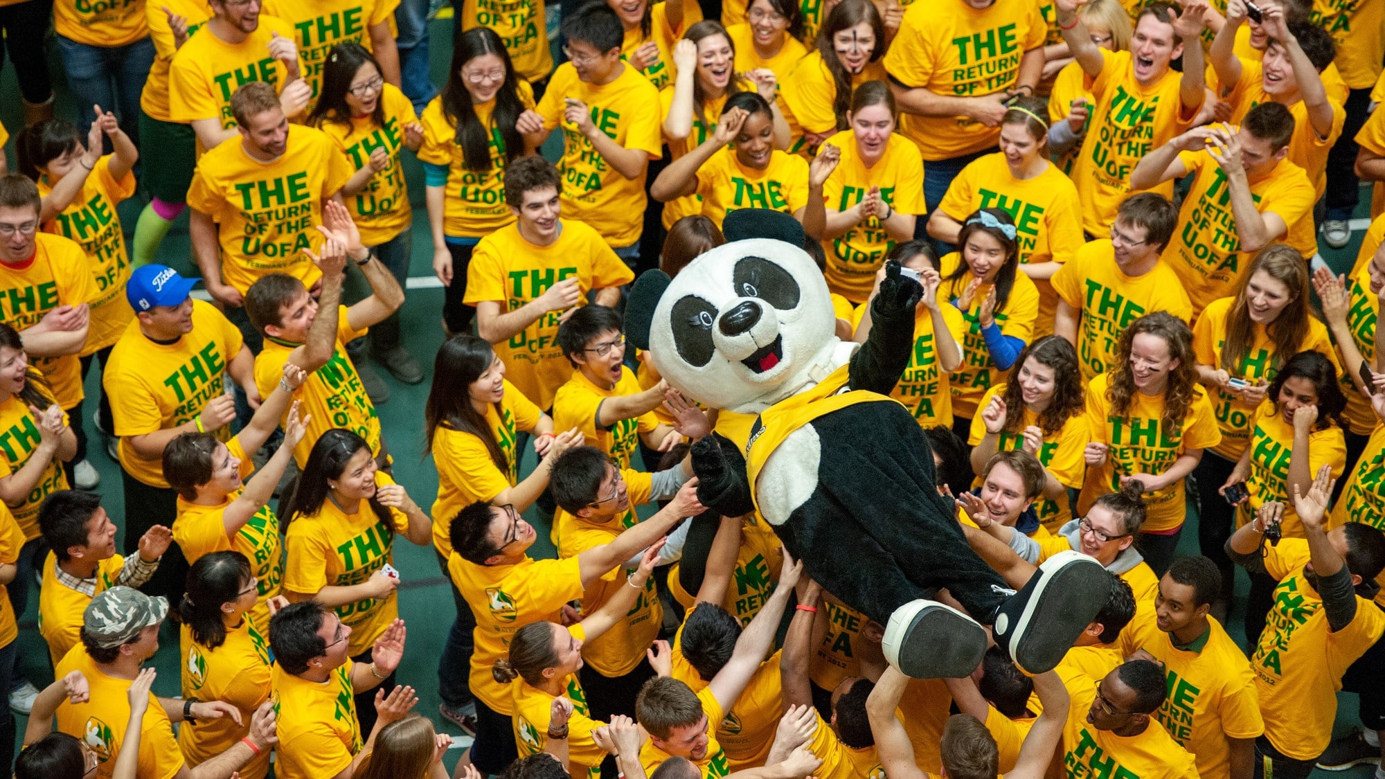 Patches the mascot crowd surfing over students wearing Green and Gold after a dodgeball game