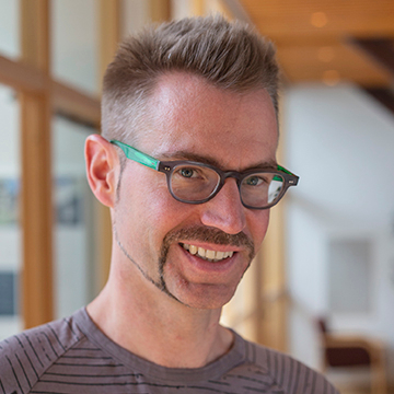 An image of Dr, Ingo Brigandt, a man indoors near a sunny window.