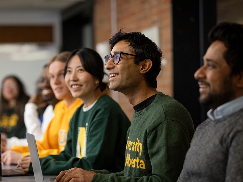 University of Alberta students sitting together during a media presentation, smiling and listening.