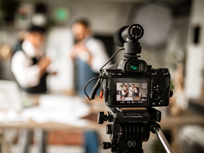 A camera recording two people during a media production session in a studio.