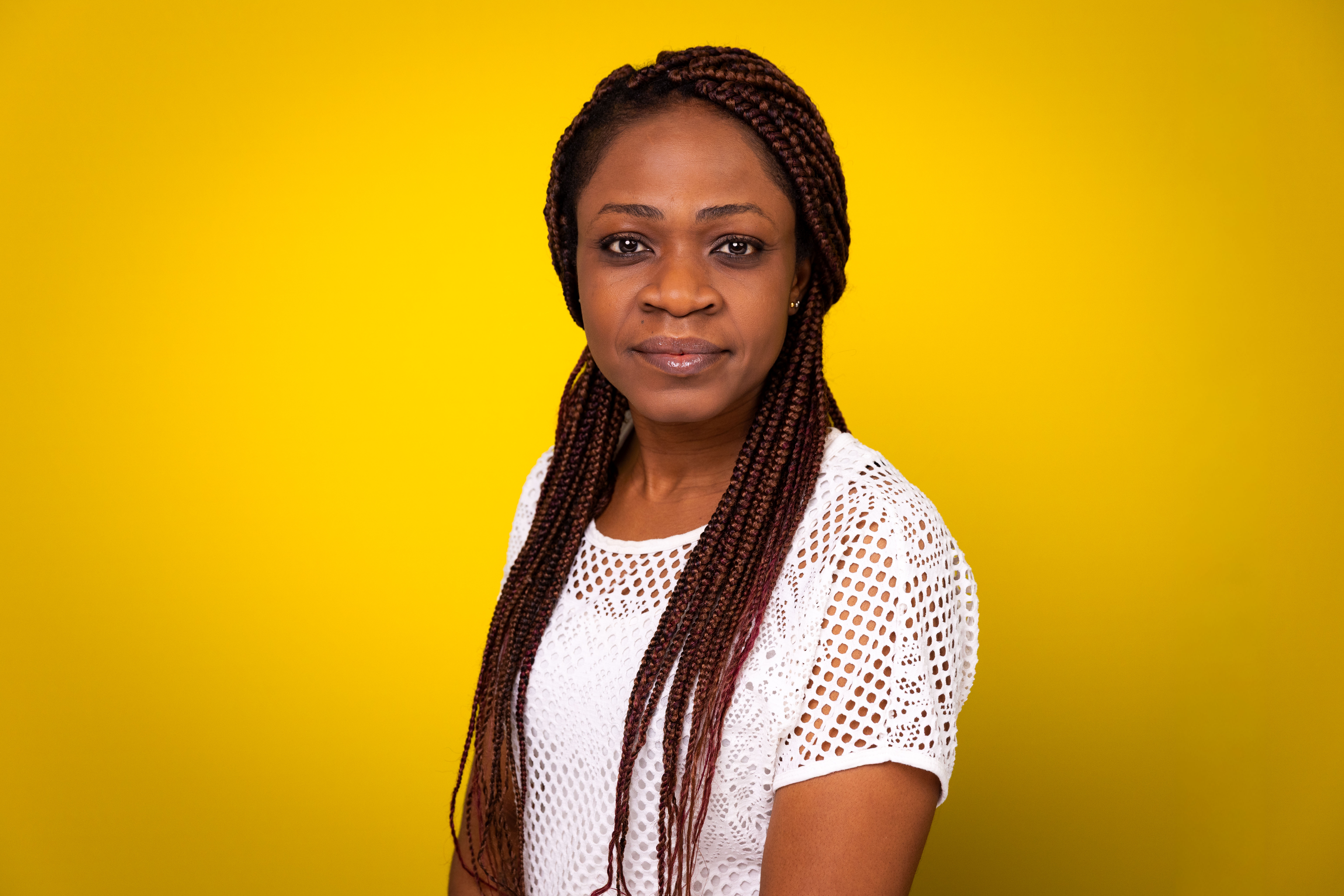 An image of Dr. Sylvia Ijeoma Madueke, a woman wearing a white shirt and standing in front of a yellow backdrop.