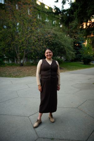 An image of Dr. Paulina Johnson, a woman wearing a brown dress and standing outside in front of an old building.