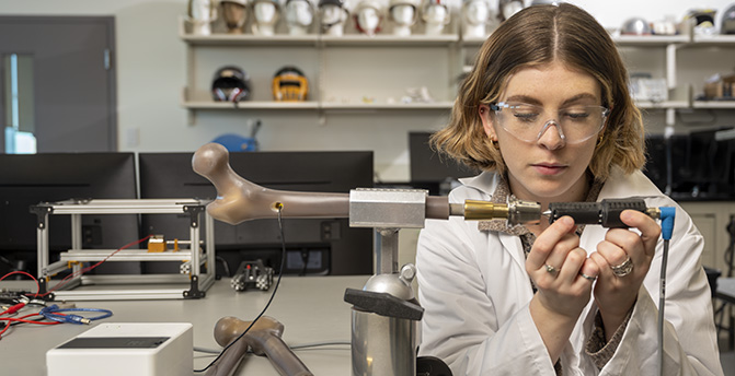 Biomechanics student in a lab works on a prosthetic.