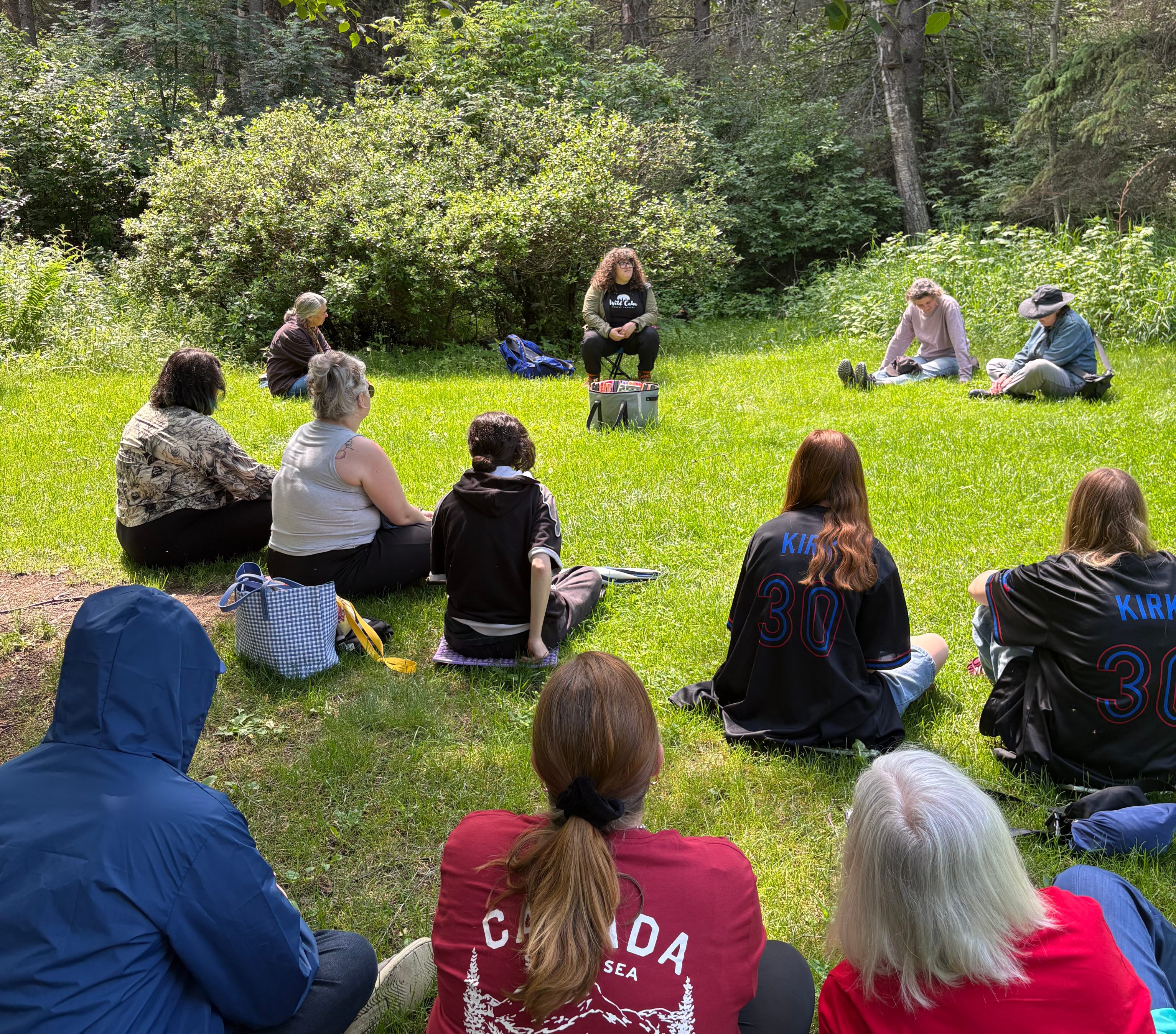 forest therapy students and teacher sitting on the ground in a semicircle