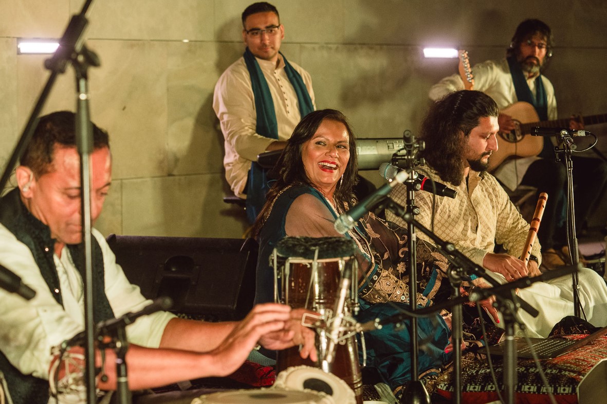 Shabnam Merali smiling while performing at night in the Amphitheatre