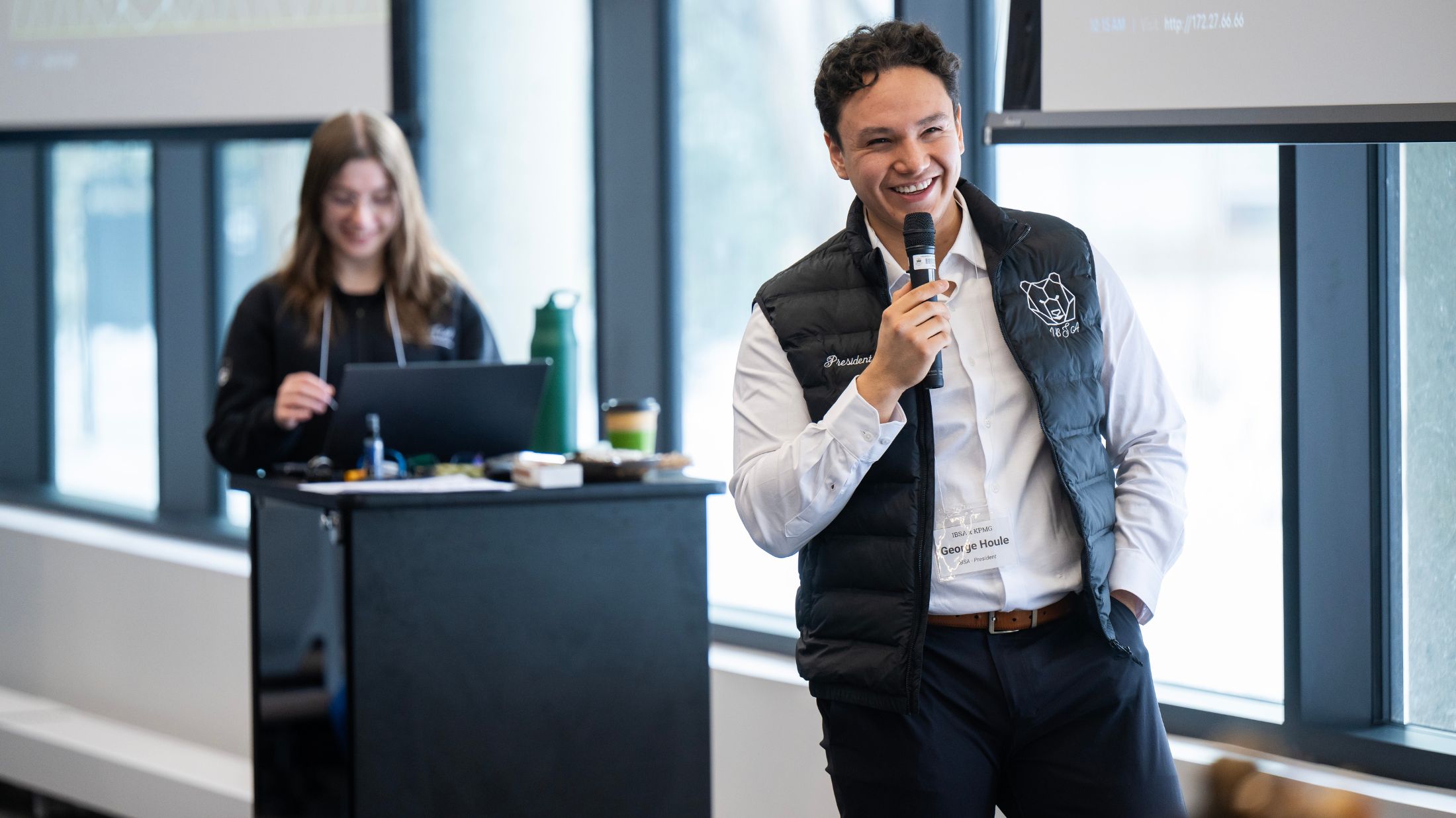 Two Indigenous students are standing in the front of a room presenting.