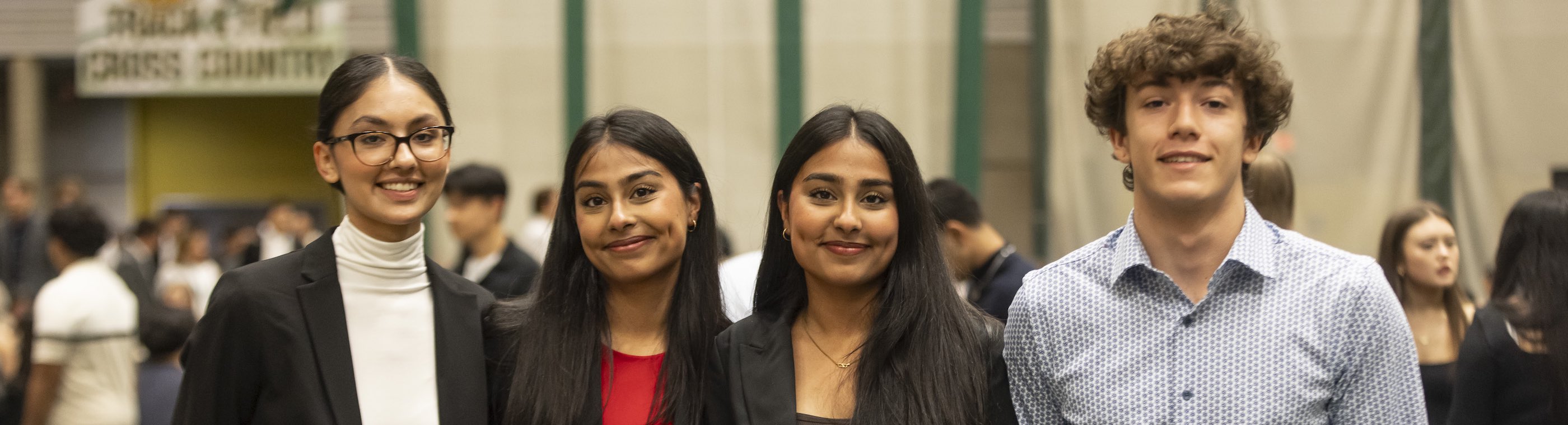 Four business students lined up smiling