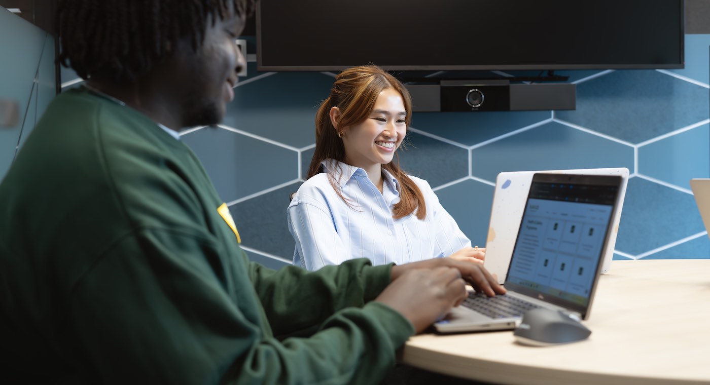 Two students study on their laptops at a table