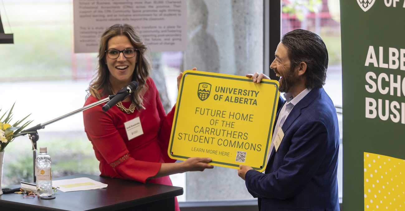 Two people holding a sign for the Future Home of the Carruthers Student Commons at a fundraising announcement