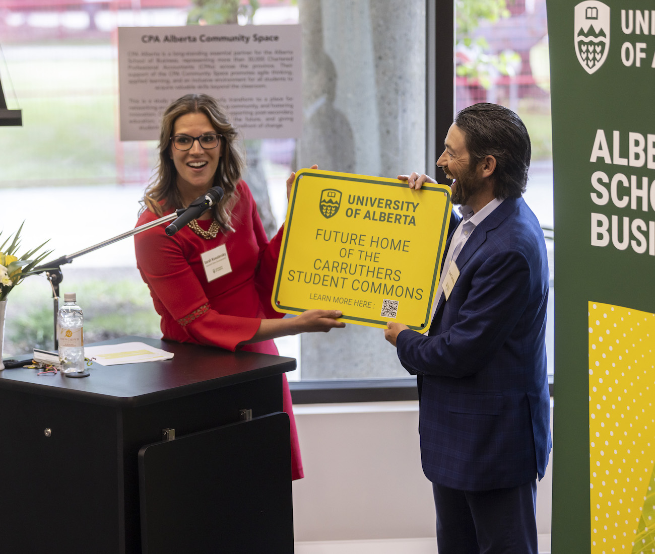 Two people holding a sign for the Future Home of the Carruthers Student Commons at a fundraising announcement