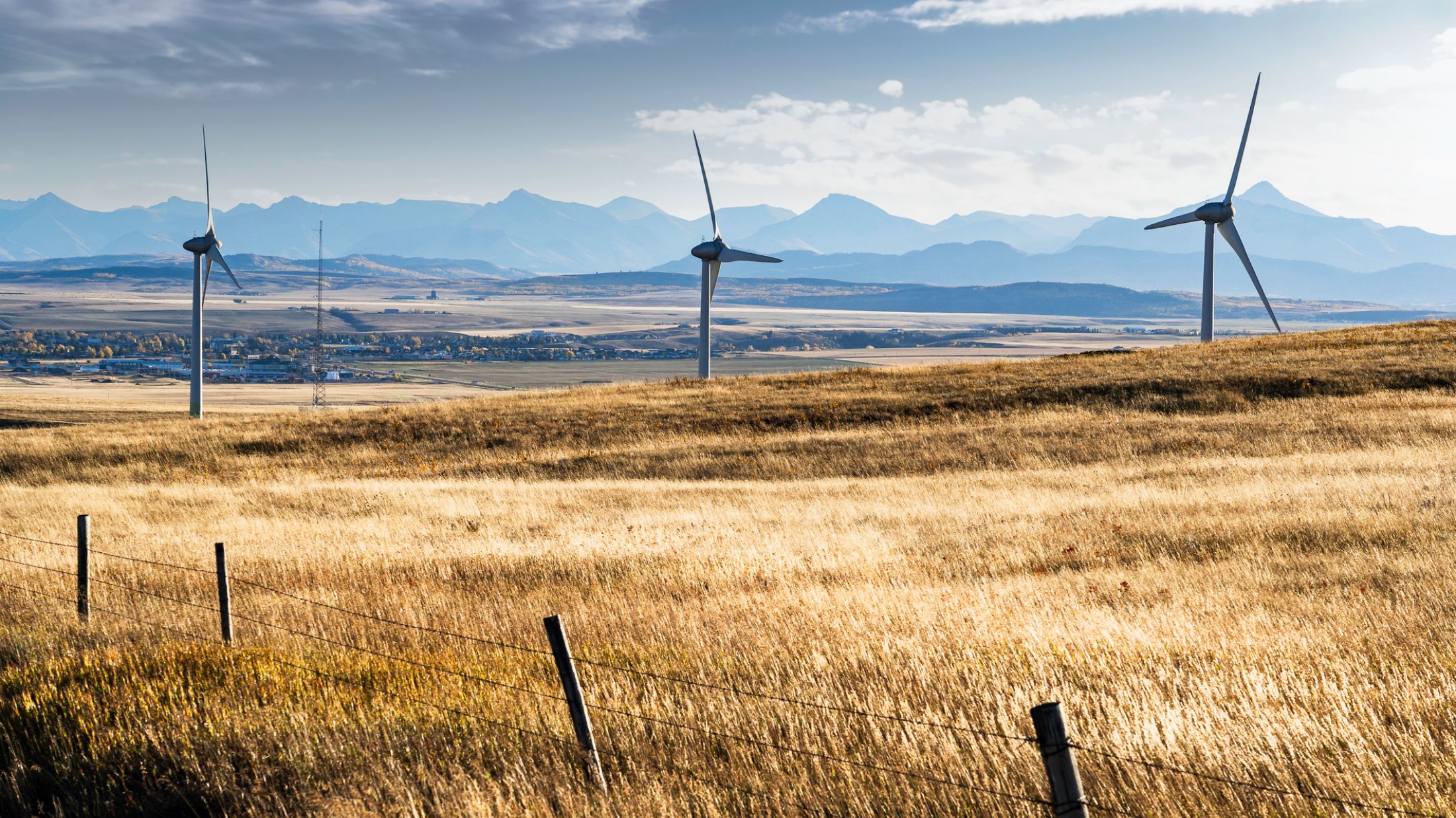 Wind turbines overlook the town of Pincher Creek Alberta and the Crowsnest Pass with Rocky Mountains at background in Western Canada.