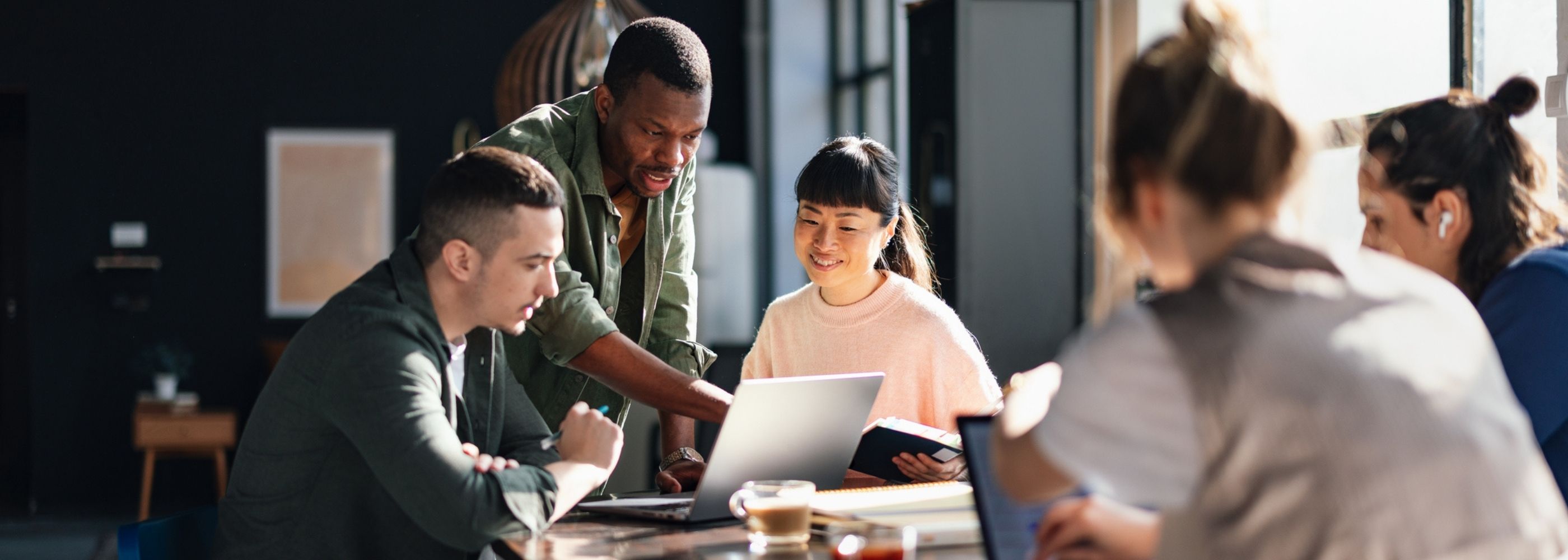 Young professionals or students collaborating in a bright, contemporary co-working environment, displaying teamwork and productivity.  
