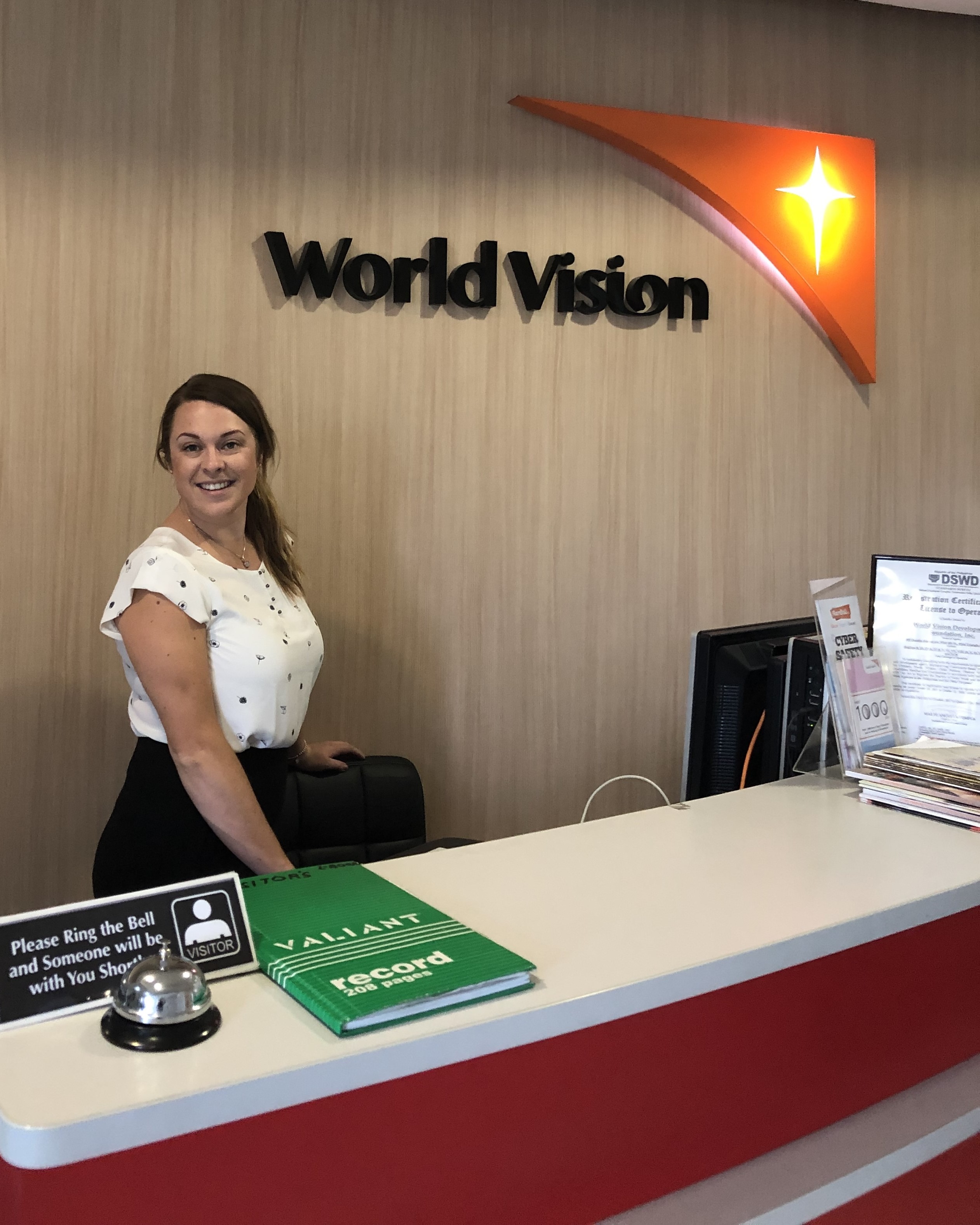 Elise standing at a desk in a World Vision office
