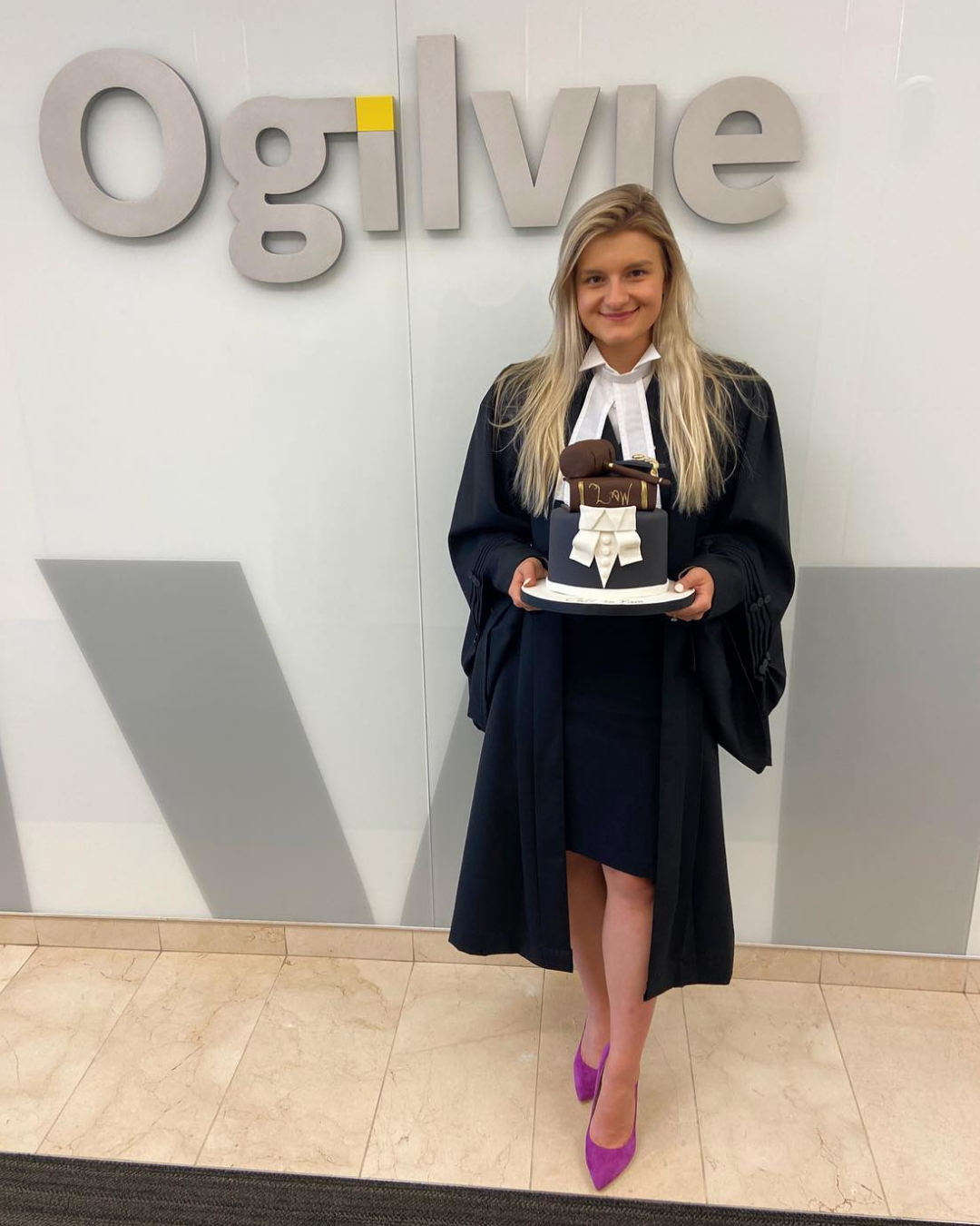Jacquelyn Zimmerman stands in front of an Ogilvie sign wearing purple heels
