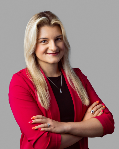 Jacquelyn Zimmerman headshot, wearing a red blazer against a grey backdrop