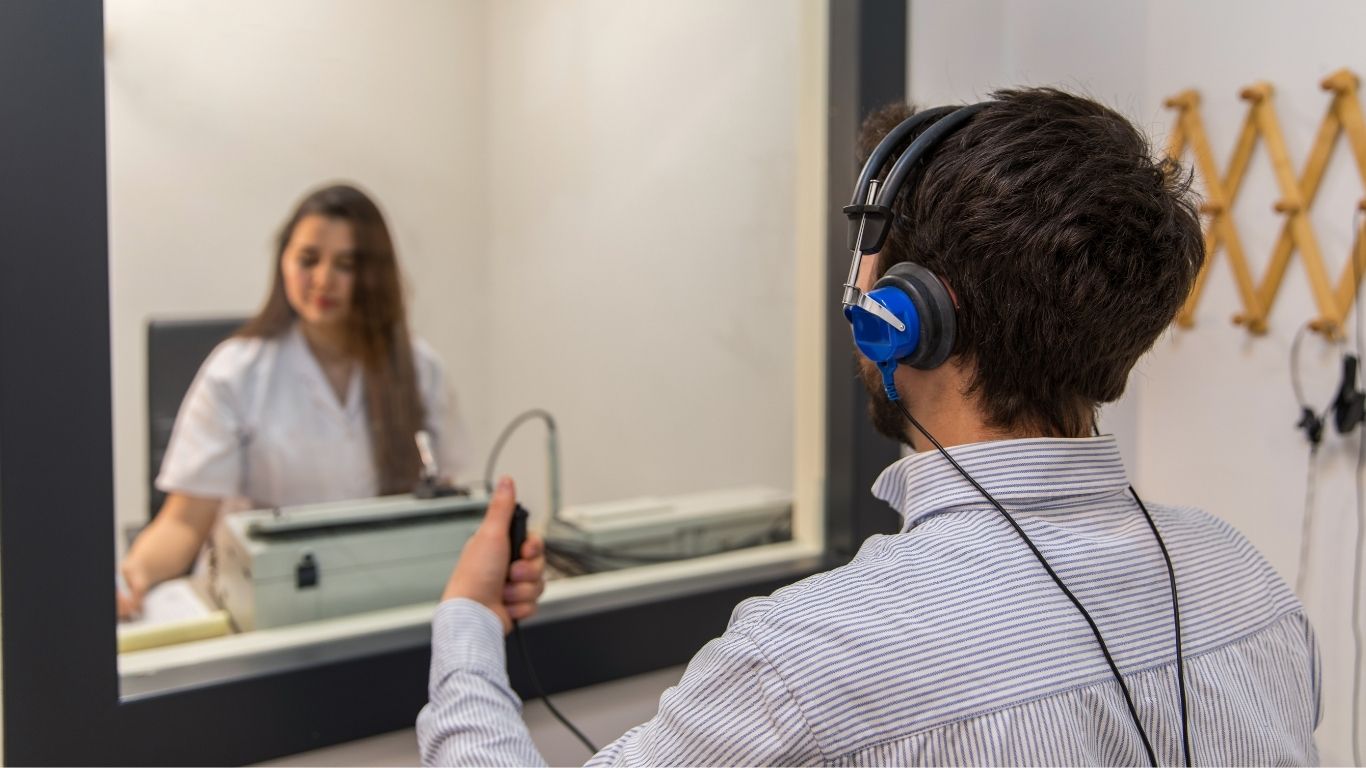 Person wearing headphones and holding button while looking at therapist