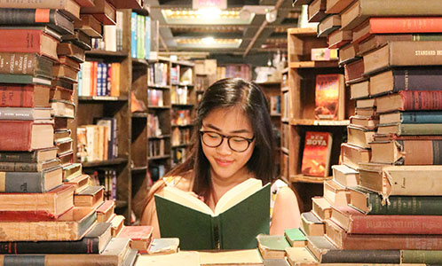 Student reading surrounded by books