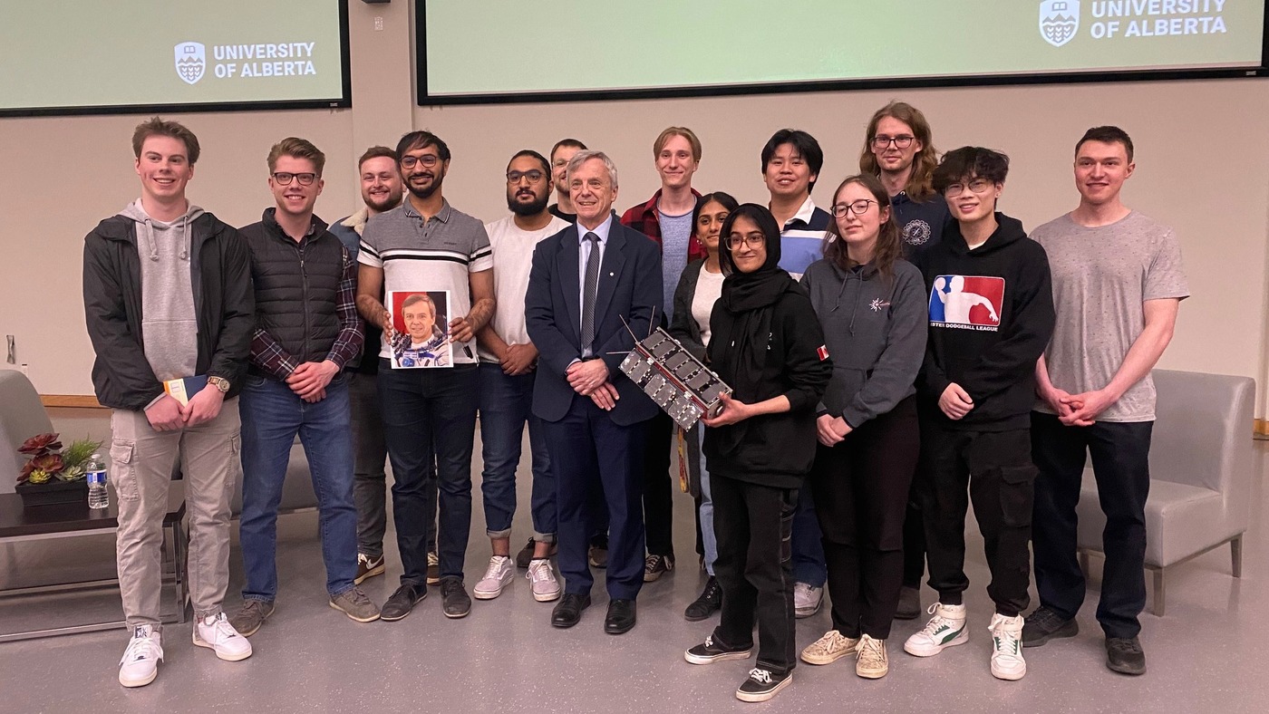 Engineering students pose at front of classroom with alumni.